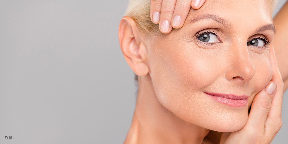 Older beautiful woman with hands on her face.